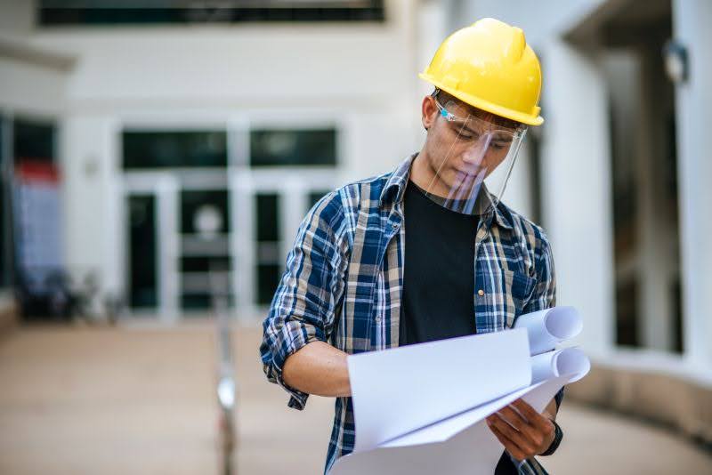 staviteľ drží v rukách dokumenty k stavbe